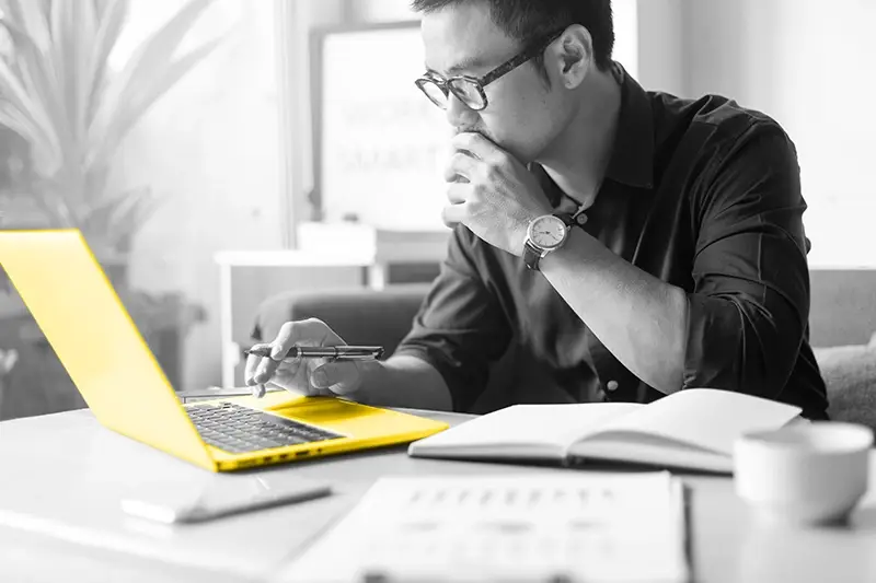 A man looking at a yellow laptop