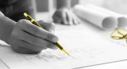 A person drawing blueprints with a yellow pen