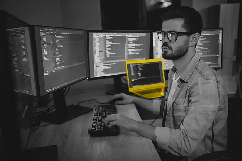 Worker in a dark room surrounded by monitors