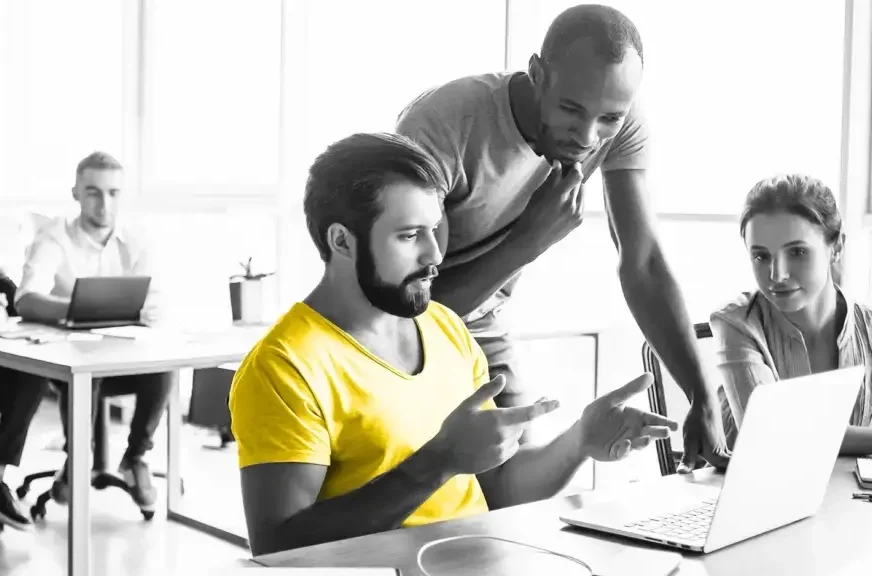 Three people talking around a laptop