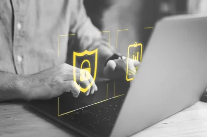 Icon of shield with lock and charts in yellow over black and white photo of man's hands typing on laptop