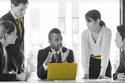 Team meeting around a yellow laptop