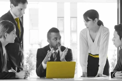 Team meeting around a yellow laptop