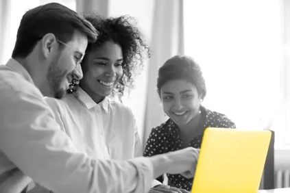 3 people looking at a yellow laptop
