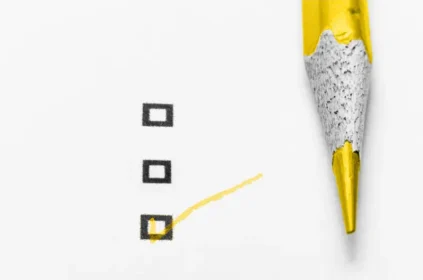 Gold colored pencil making a check in a box