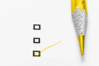 Gold colored pencil making a check in a box