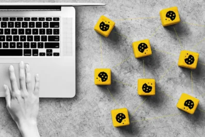 Hand on a laptop with wooden blocks next to them. Cookie icon on each block.
