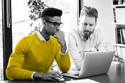 Two co-workers looking at a laptop