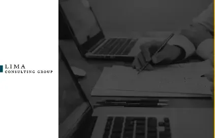 Hands writing on a piece of paper next to a computer