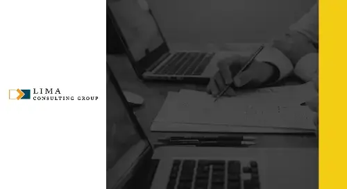 Hands writing on a piece of paper next to a computer